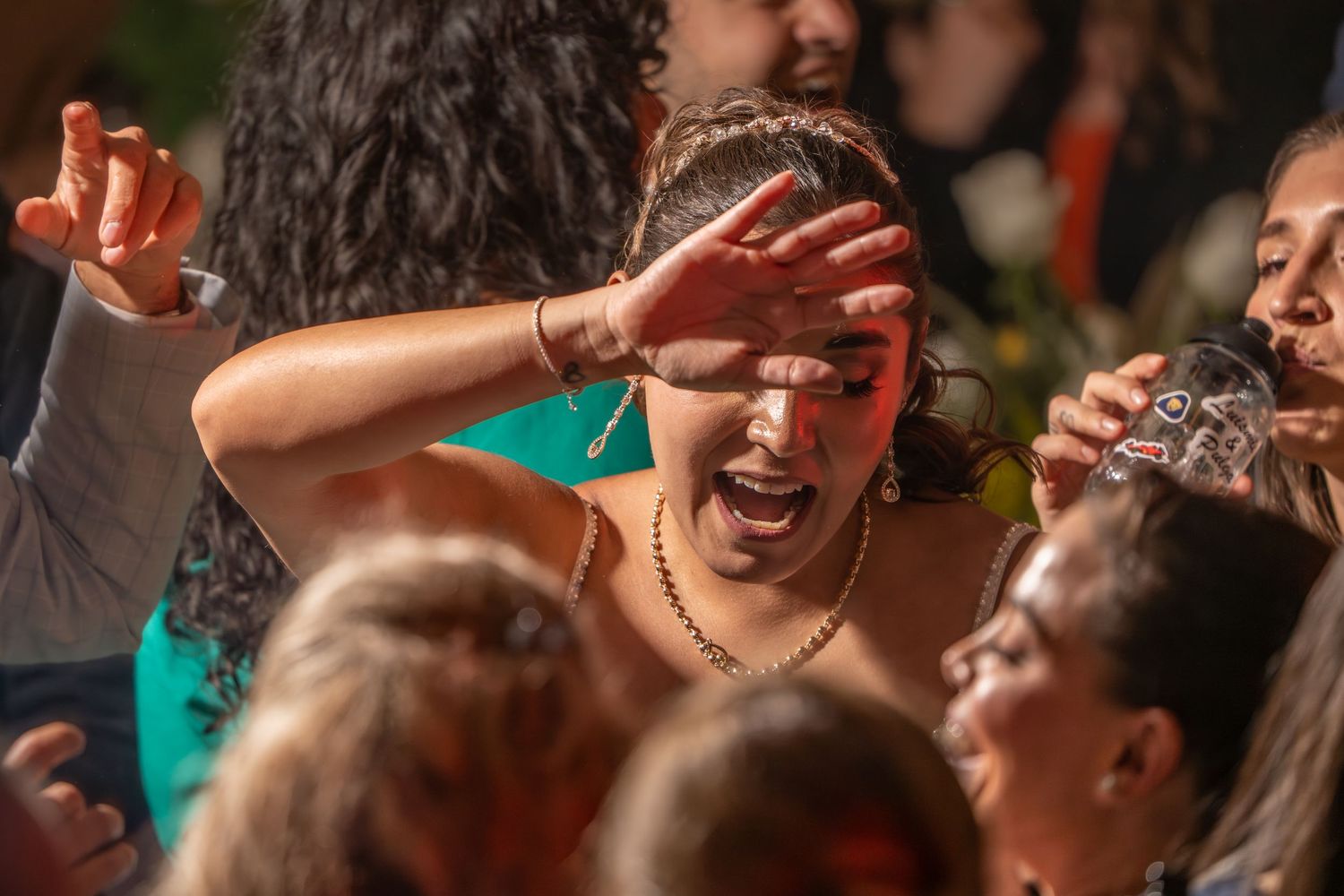 People dancing and celebrating at a lively party with drinks and joyful expressions.