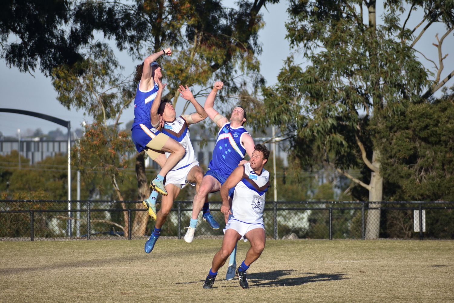 Footy players jumping at the incoming ball - sports photography