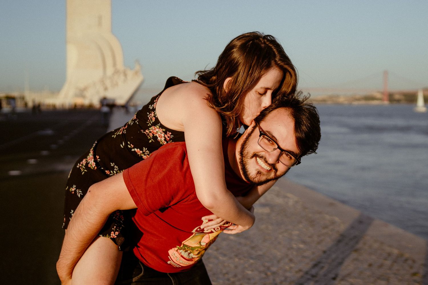 Two people play and laugh together on a sunny beach at sunset.