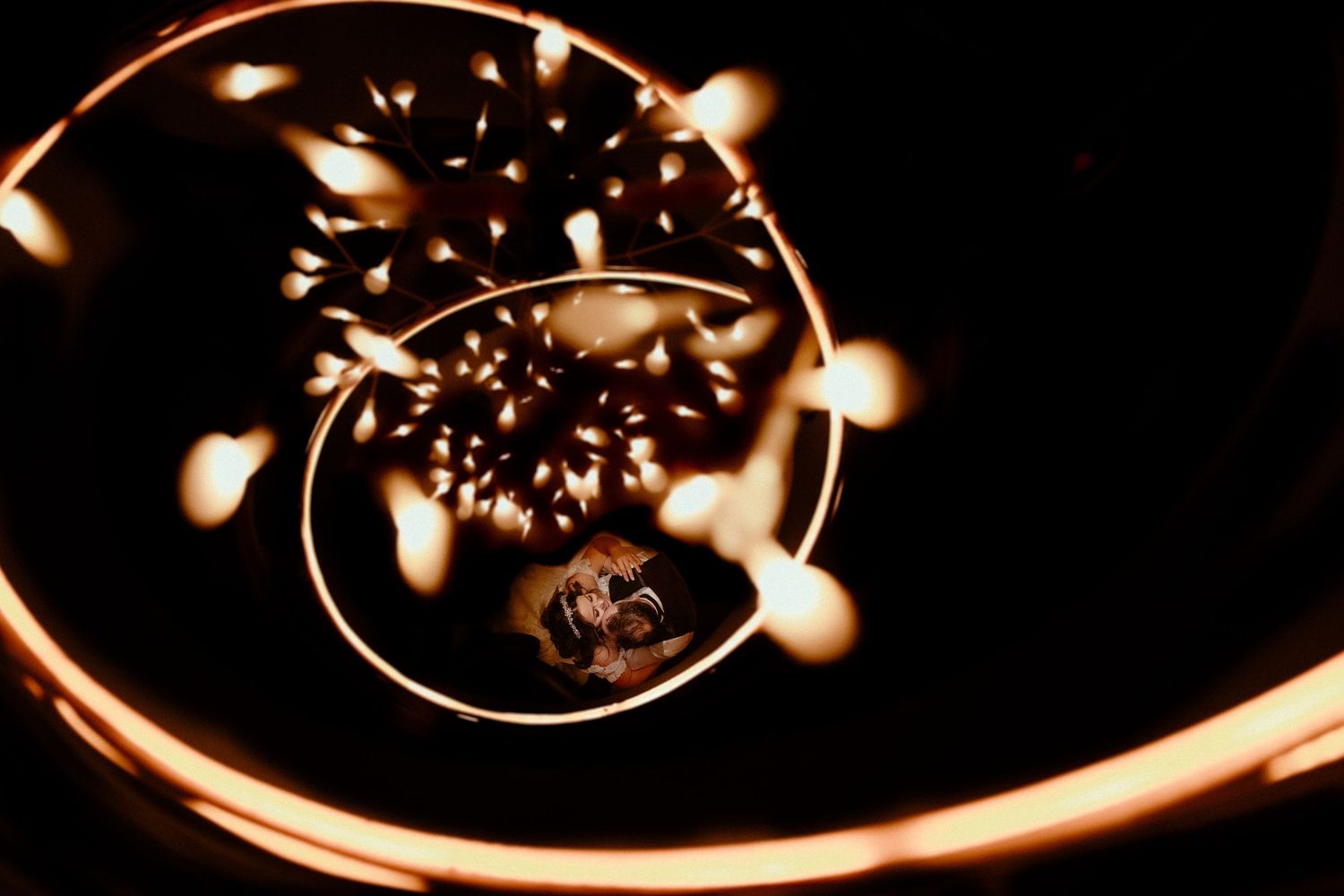 Abstract light trails create glowing spiral patterns against a dark background.