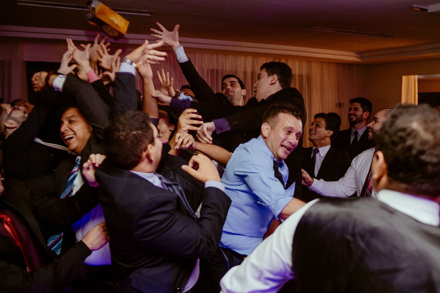 Wedding reception dance floor filled with guests under ambient lighting.