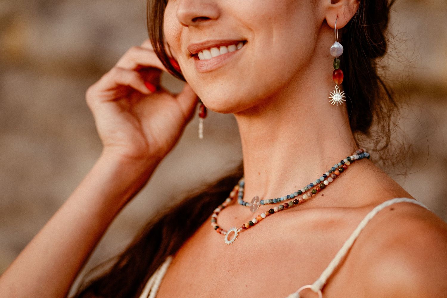 Close-up portrait of an elegant smile with sparkly jewelry and delicate shoulder straps.