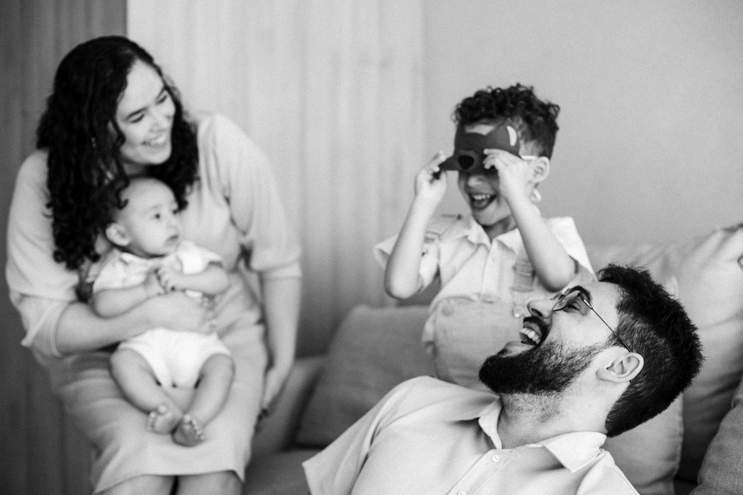 Black and white candid family moments showing joy and laughter on a couch.