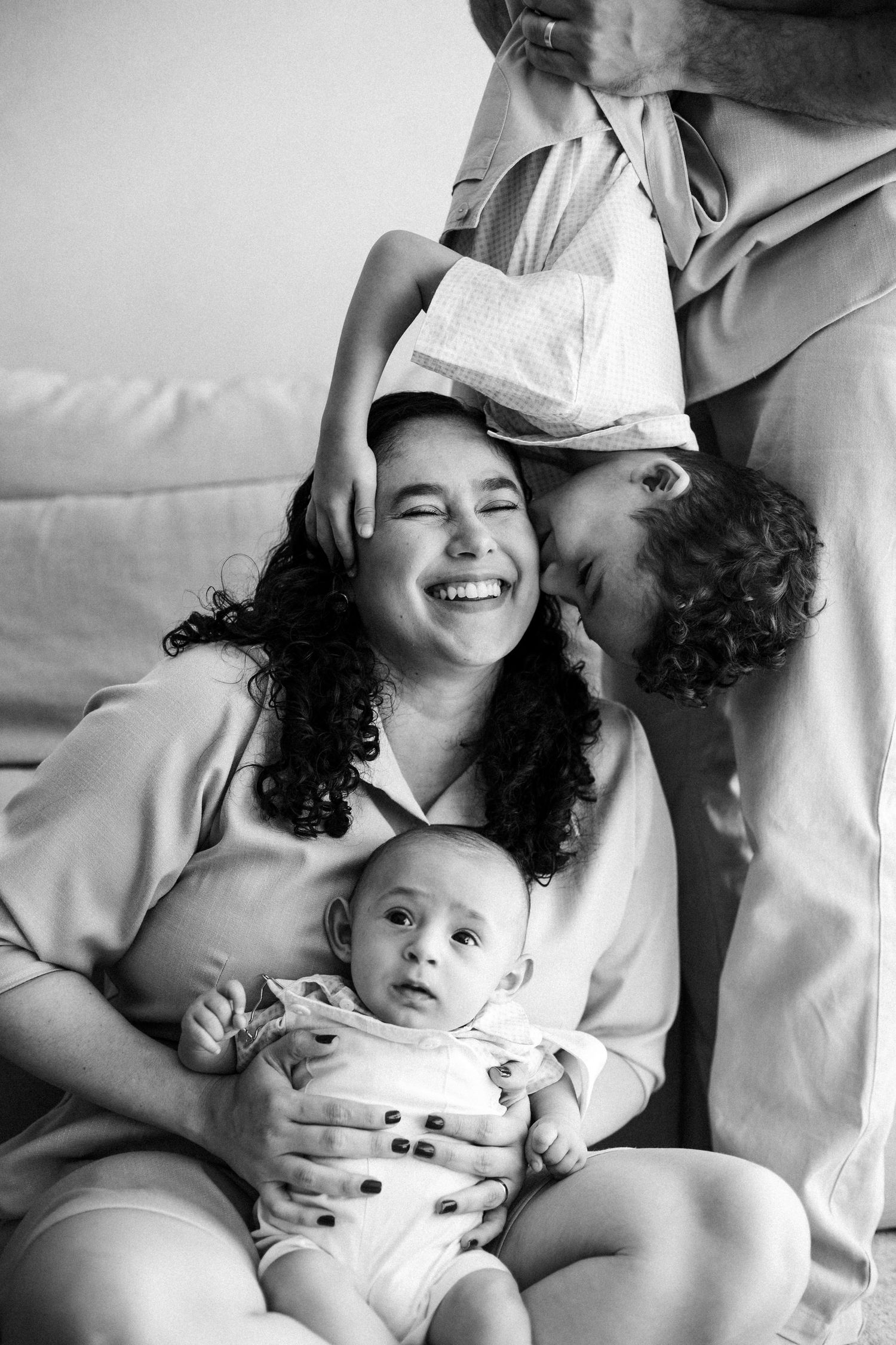 A sweet black and white photo showing a family sharing joyful laughter and tender moments together with their baby.