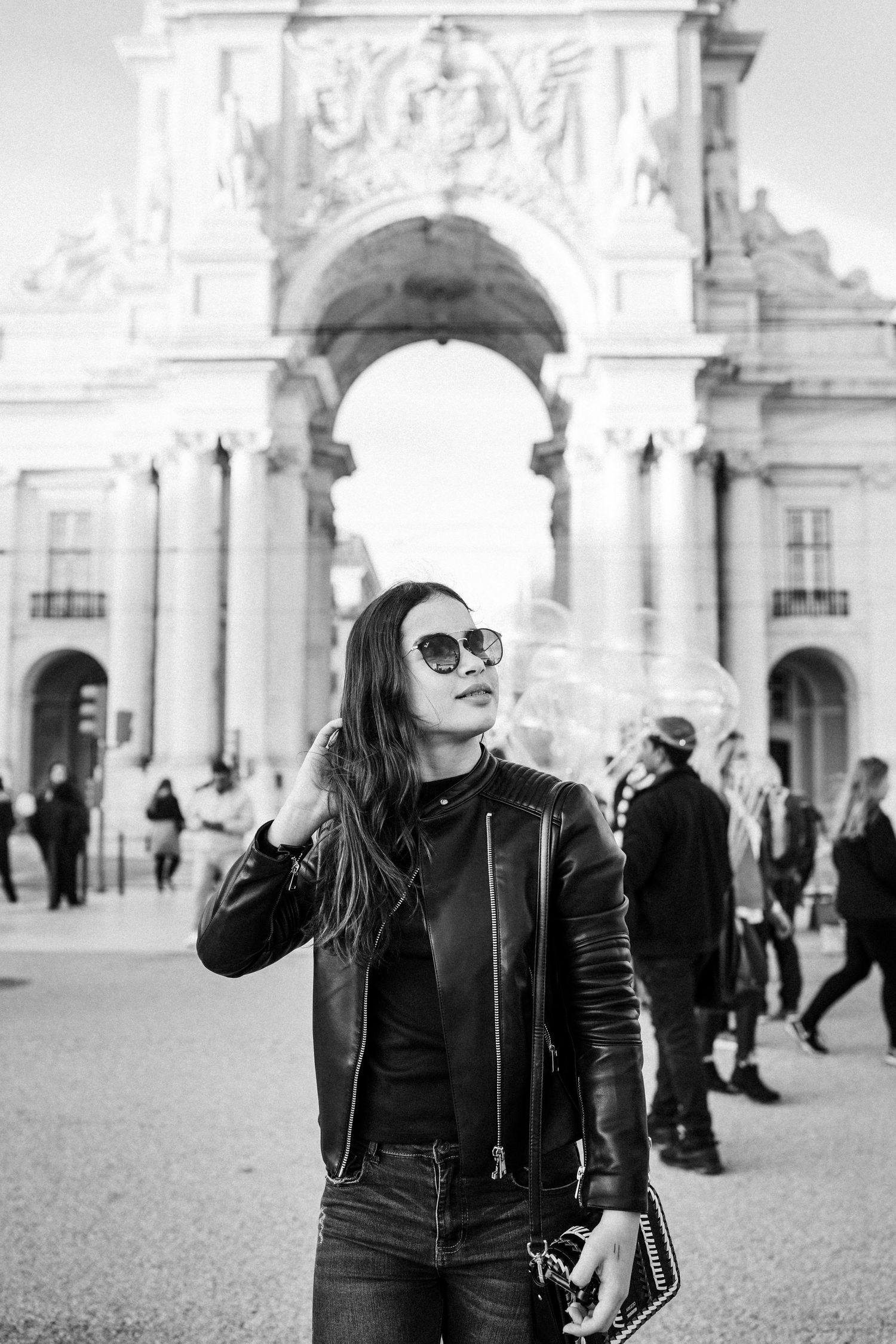 Black and white photo of tourists enjoying the grand architecture of Comercio Square in Lisbon.
