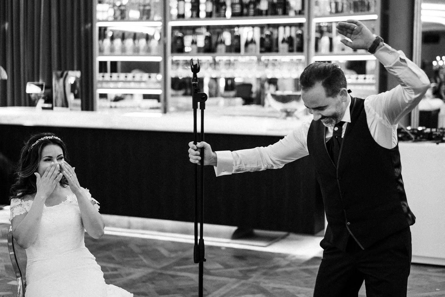 Black and white photo of bride and groom dancing energetically at their wedding reception.