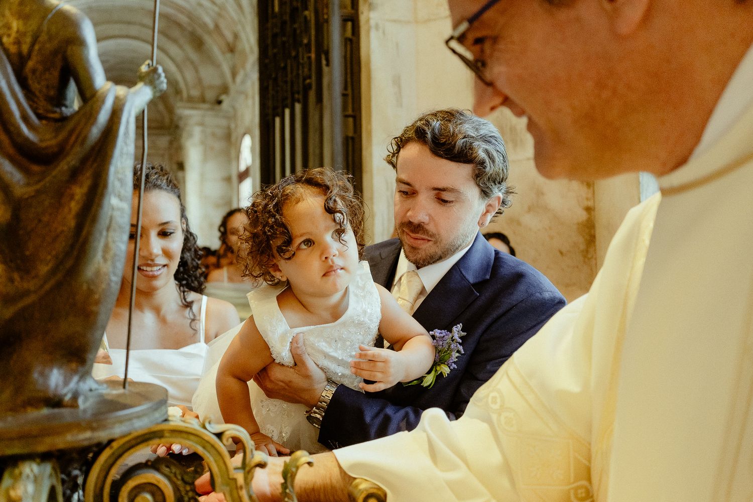 A couple with a young child participates in a Catholic wedding ceremony with a priest at the altar.