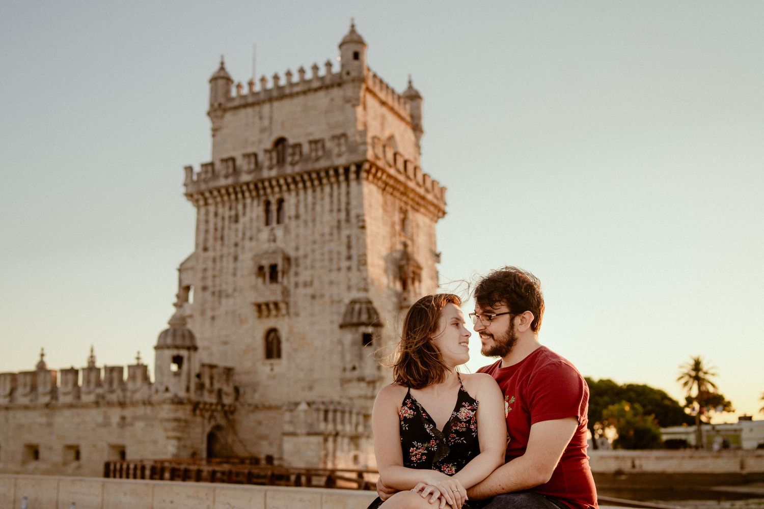 Silhouette of a couple standing in front of the historic Belem Tower in Lisbon at sunset.