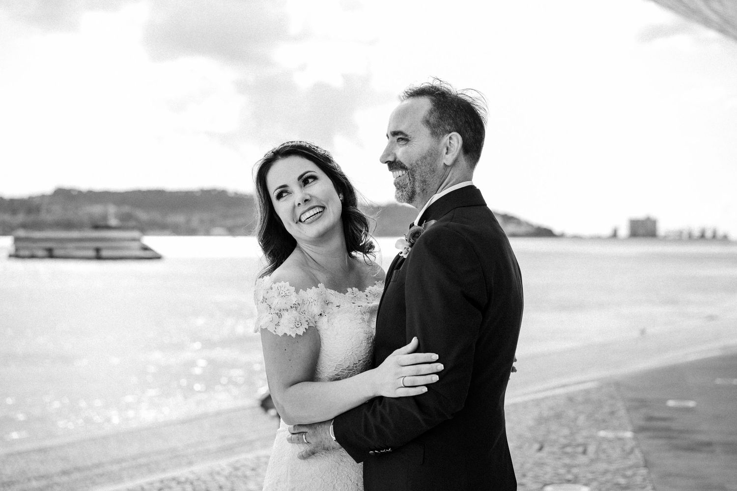 A couple shares joyful laughing moments together on the beach during sunset at the shoreline.