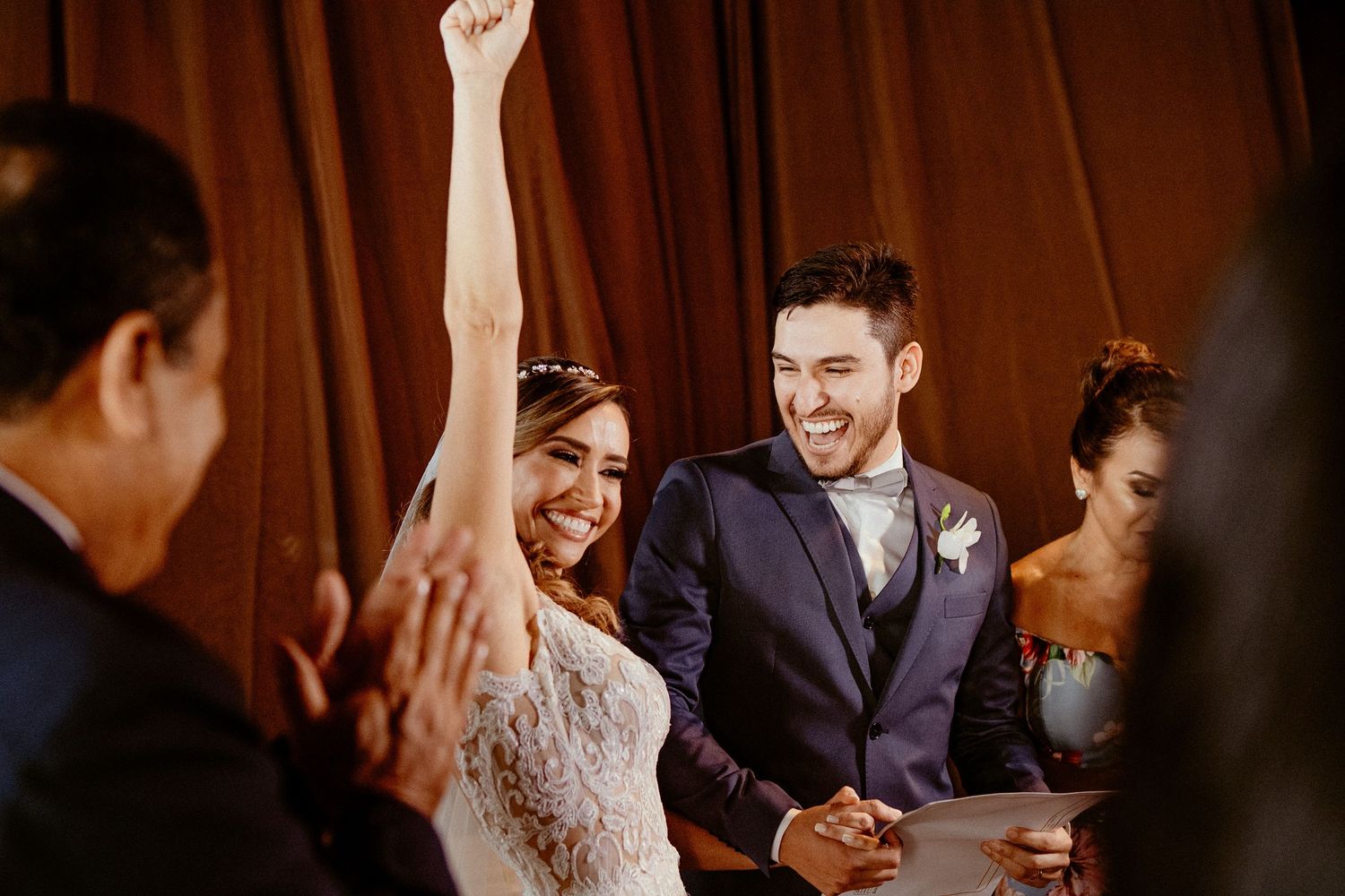 Celebratory moment during wedding ceremony with bride raising her arm in joy.