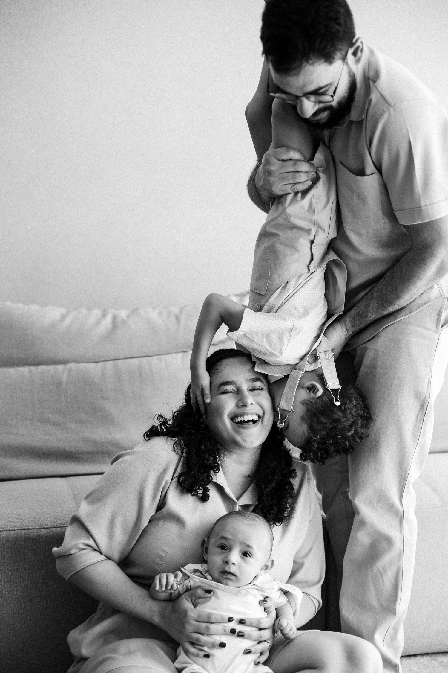 A series of intimate black and white candid photographs showing tender family moments shared between parent and child on a couch.