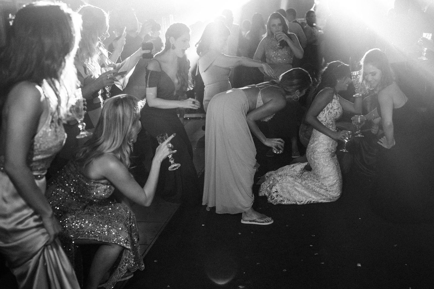 Party-goers dance and socialize at a nightclub with atmospheric lighting and smoky ambiance.