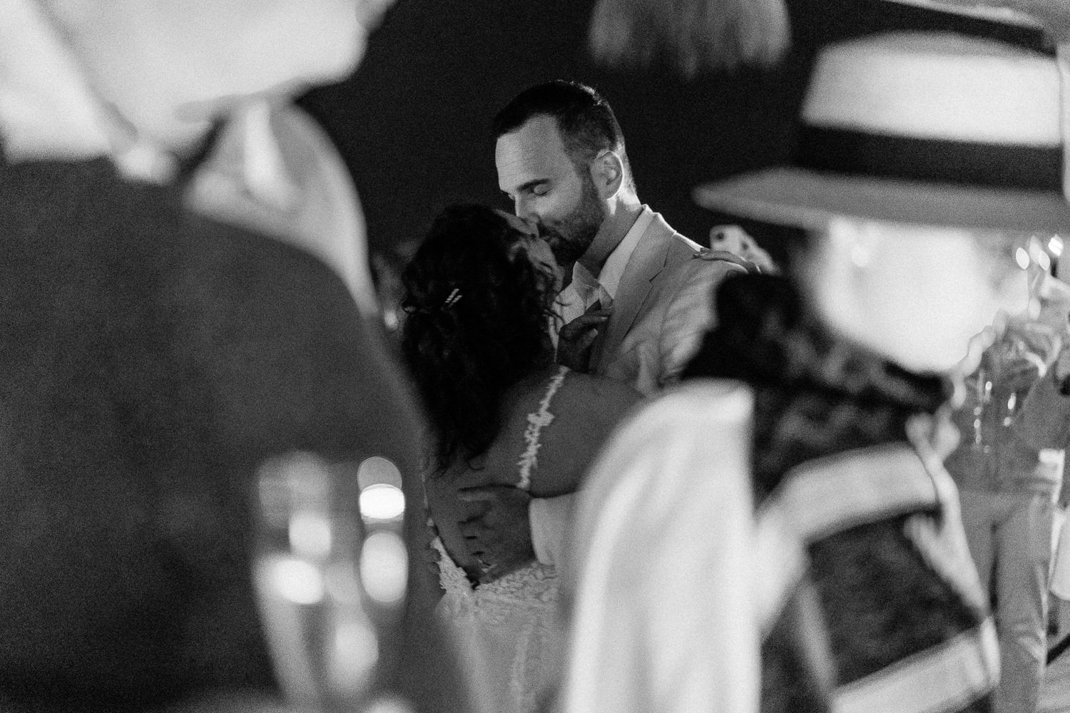 Black and white photo of a couple sharing a first dance kiss at their wedding reception.