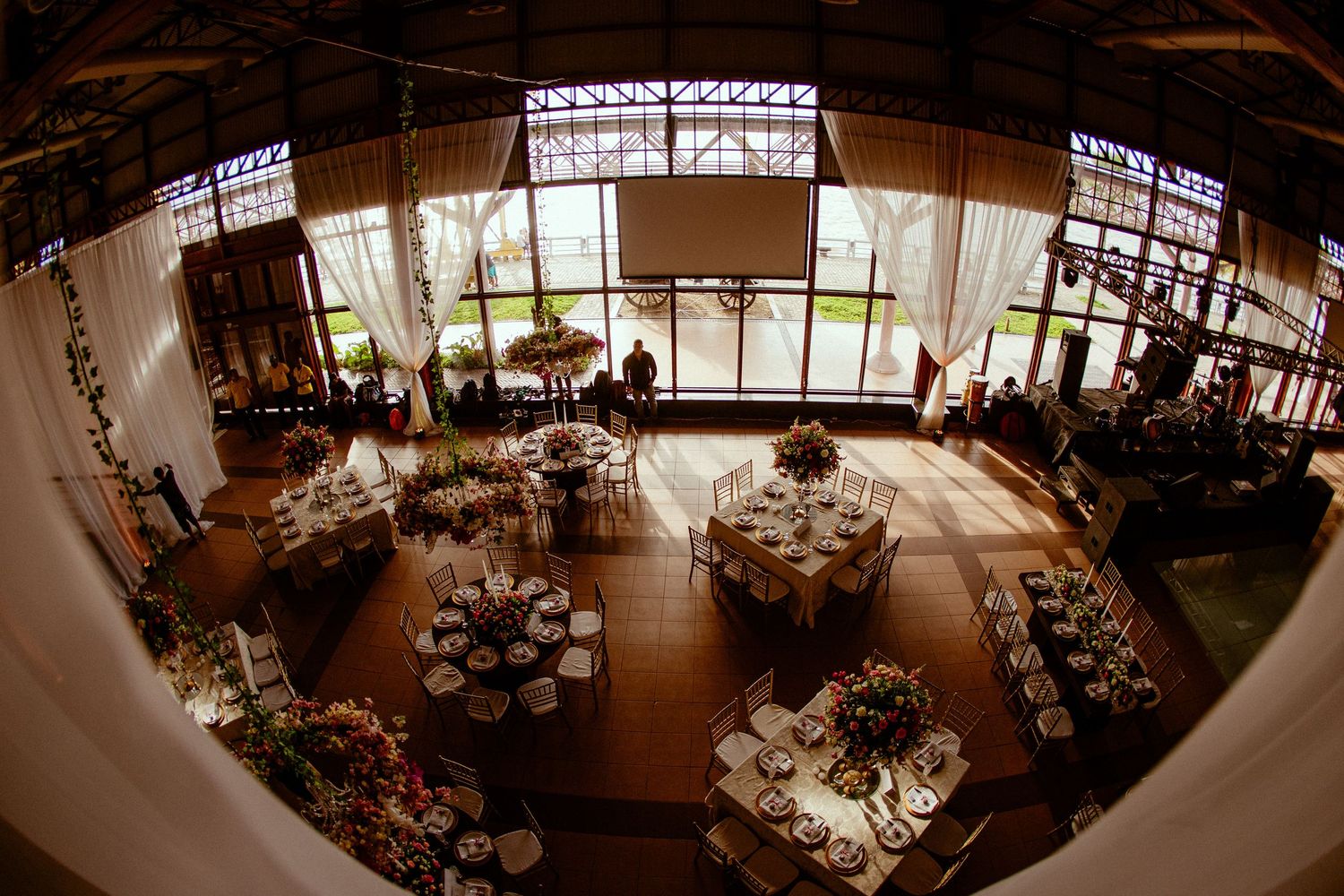 Aerial view of elegant wedding reception venue with round tables and natural lighting.