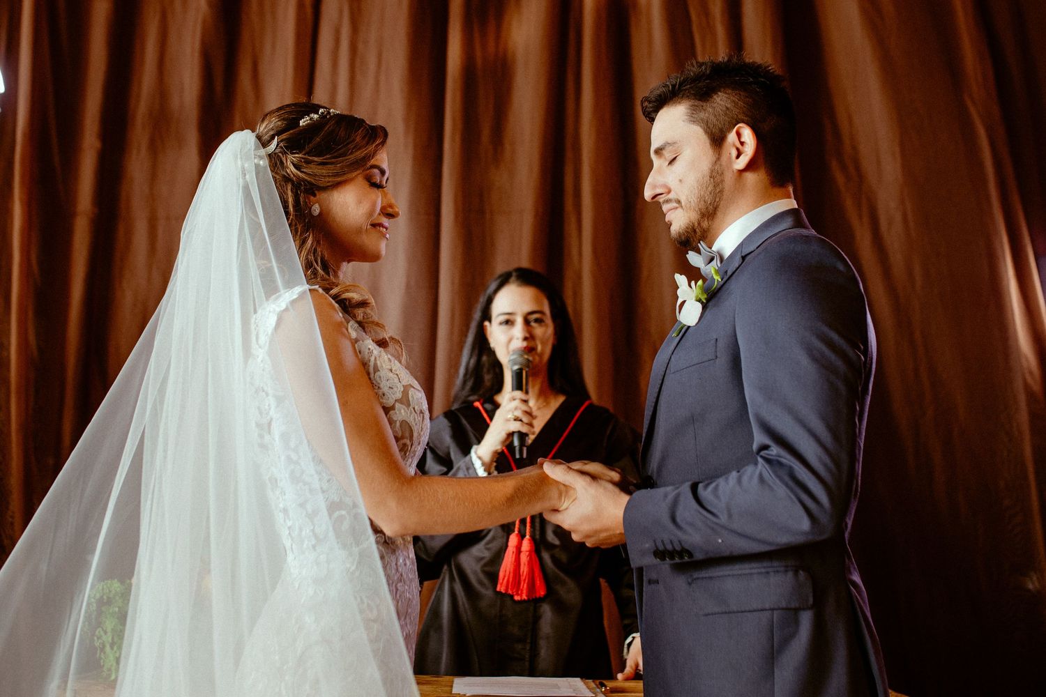 Wedding ceremony in progress with couple exchanging vows in front of an officiant.