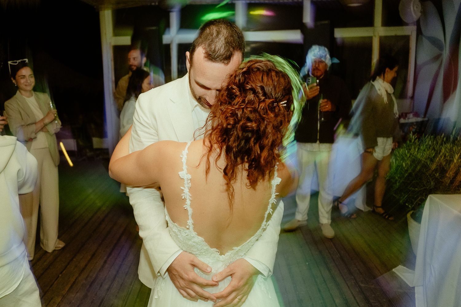 Bride and groom share their first dance, bride in backless white gown, at elegant wedding reception.