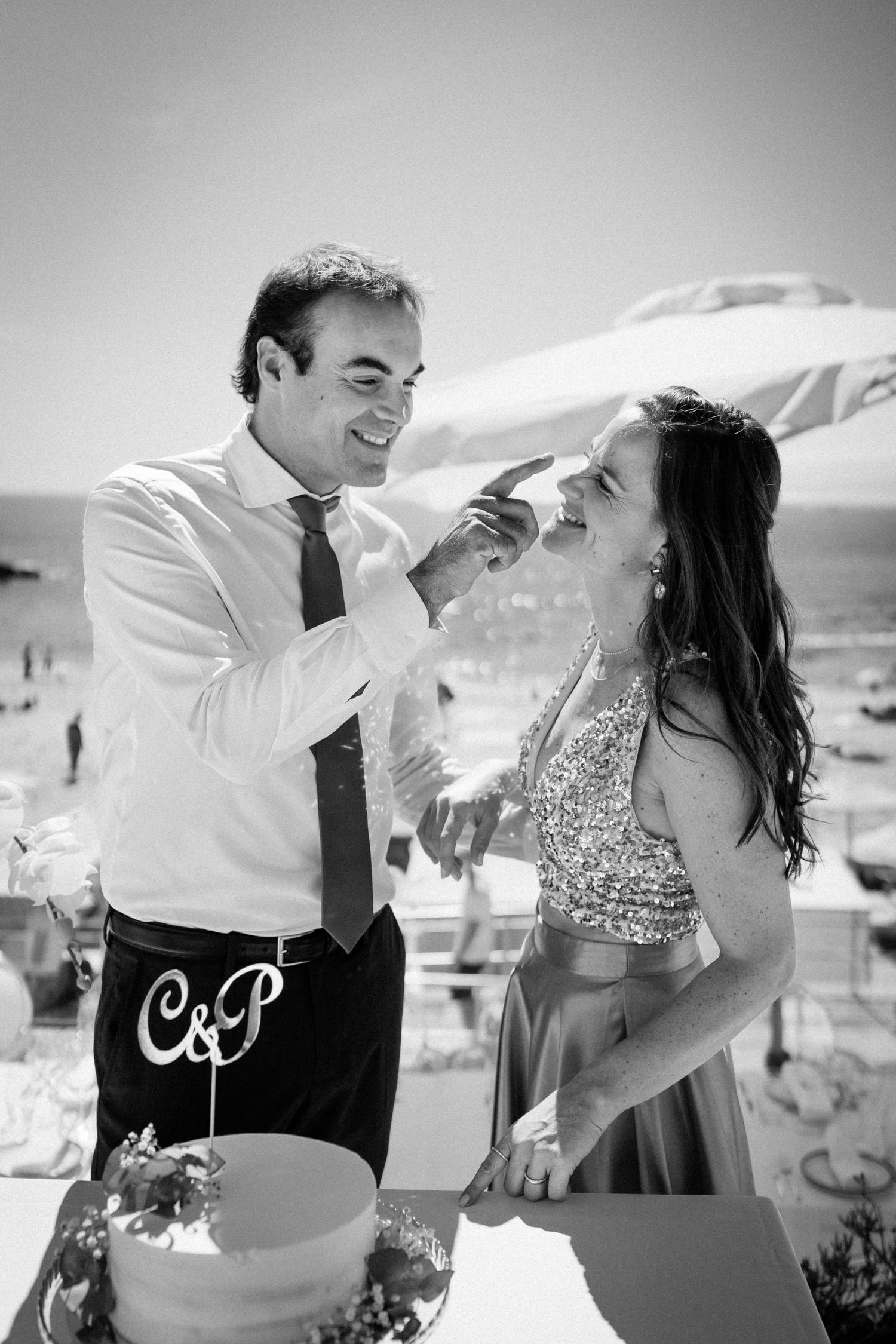 A couple shares a playful and romantic moment together at an outdoor beach location in black and white photography.