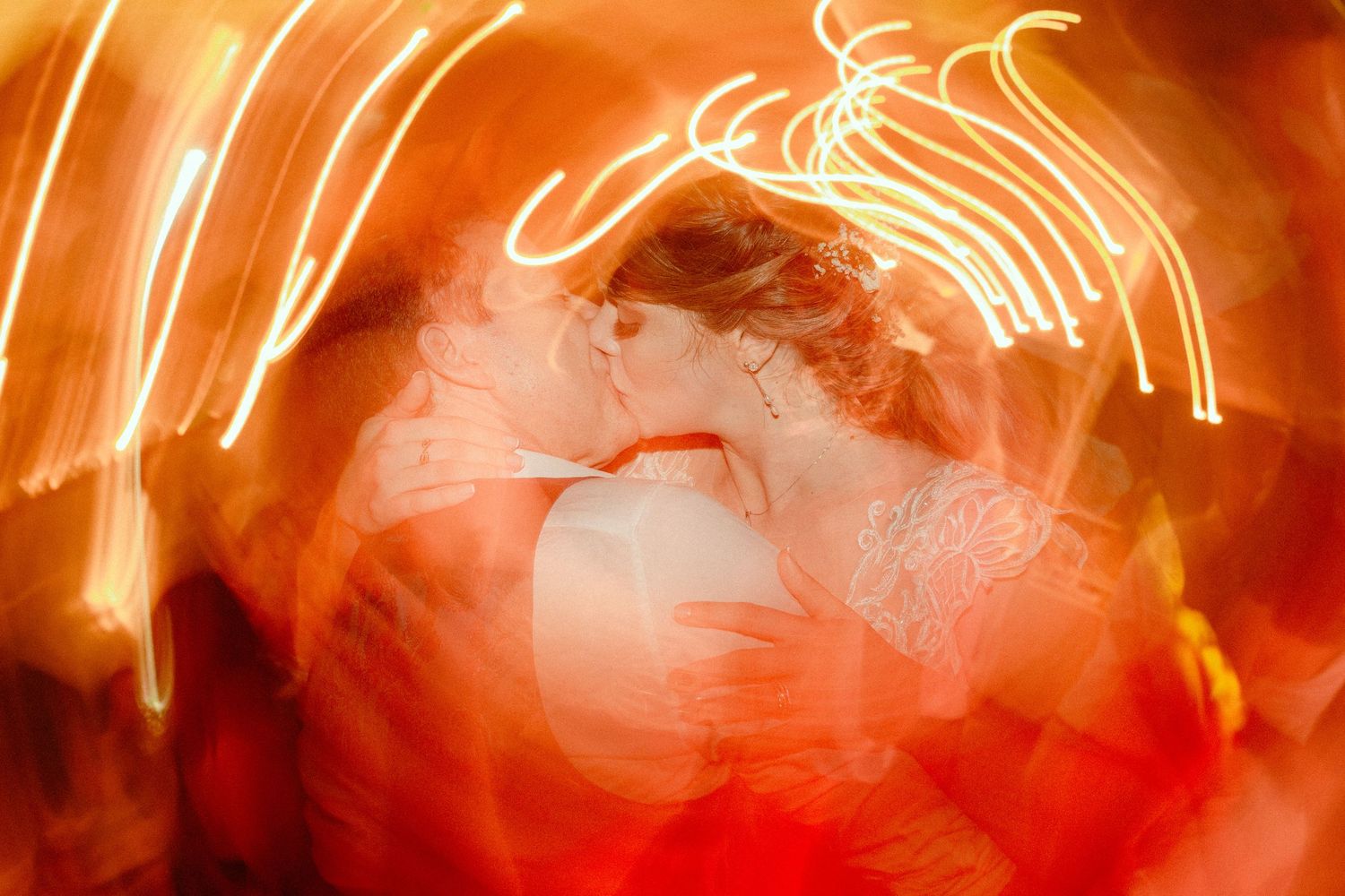 Long exposure light trails create glowing orange streaks against dark background in night photography.