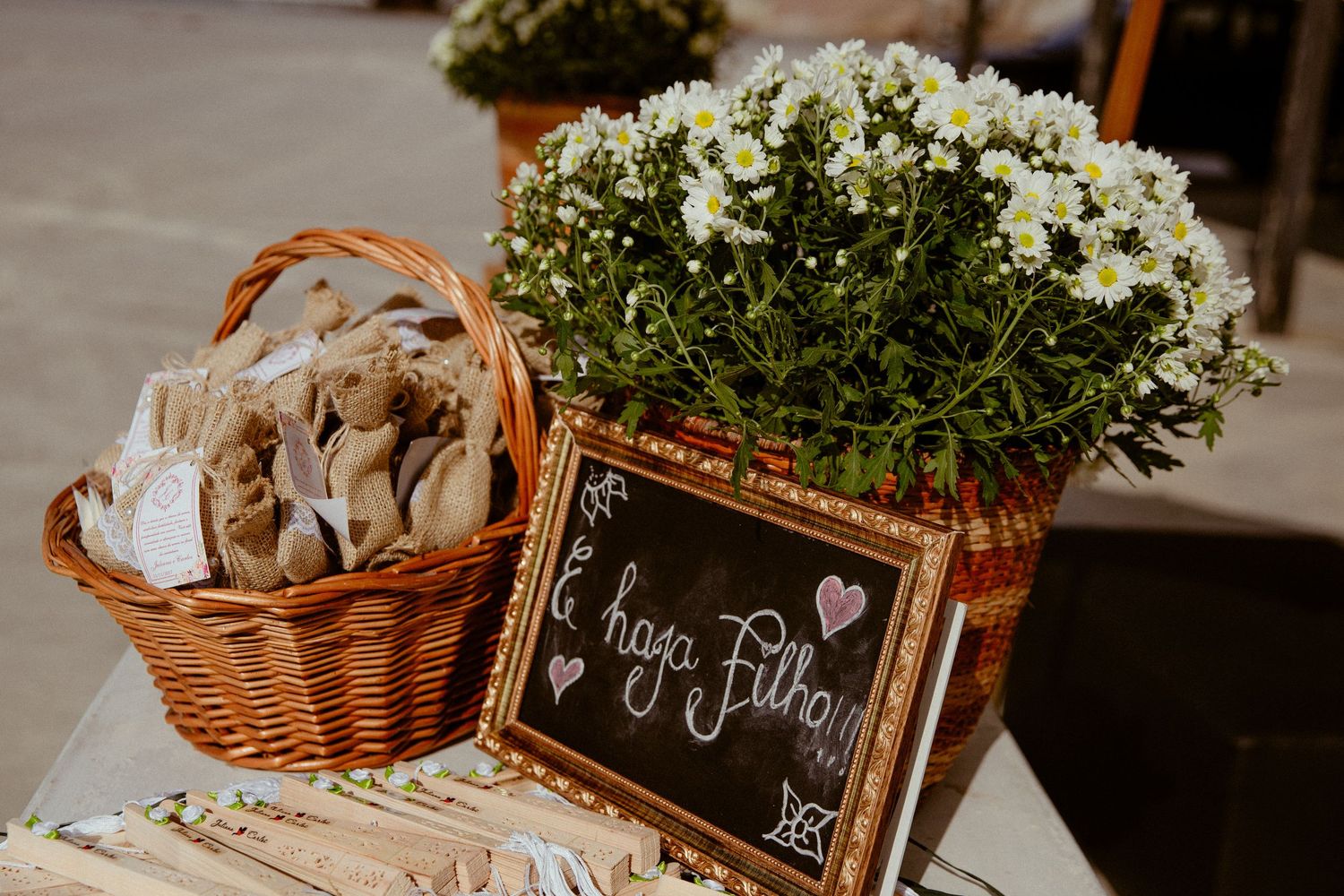 A rustic outdoor wedding reception table setup with vintage-style decor, baskets, and natural greenery accents.
