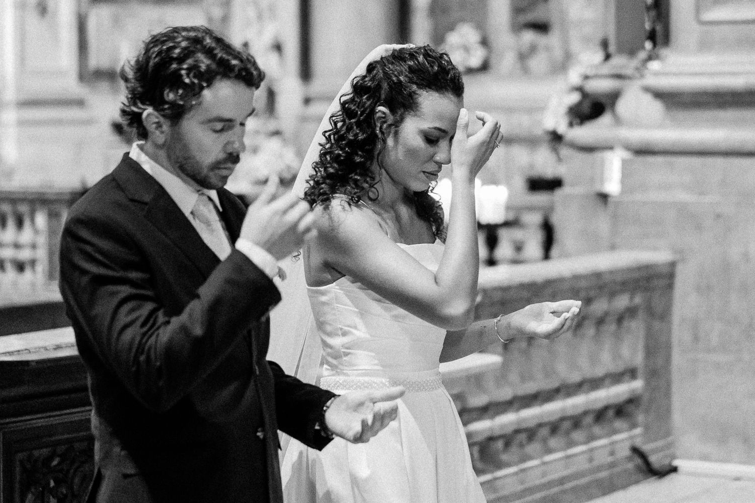 Black and white photo of a bride and groom exchanging vows during an elegant church wedding ceremony.
