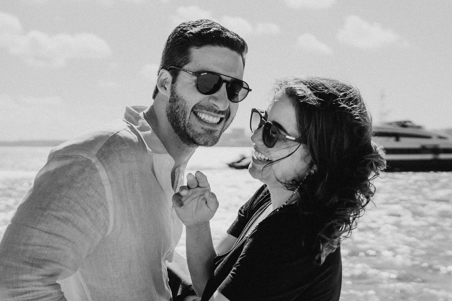 Black and white photo of a happy couple sharing a joyful moment together at the beach.
