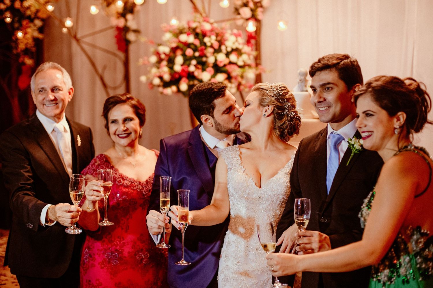 Wedding guests raise champagne glasses in celebration during an elegant reception with warm lighting.
