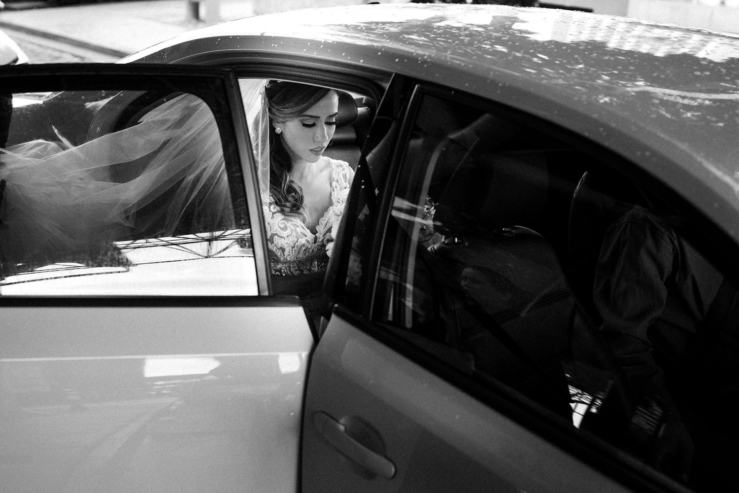 Black and white photo of departure in car after wedding celebration.