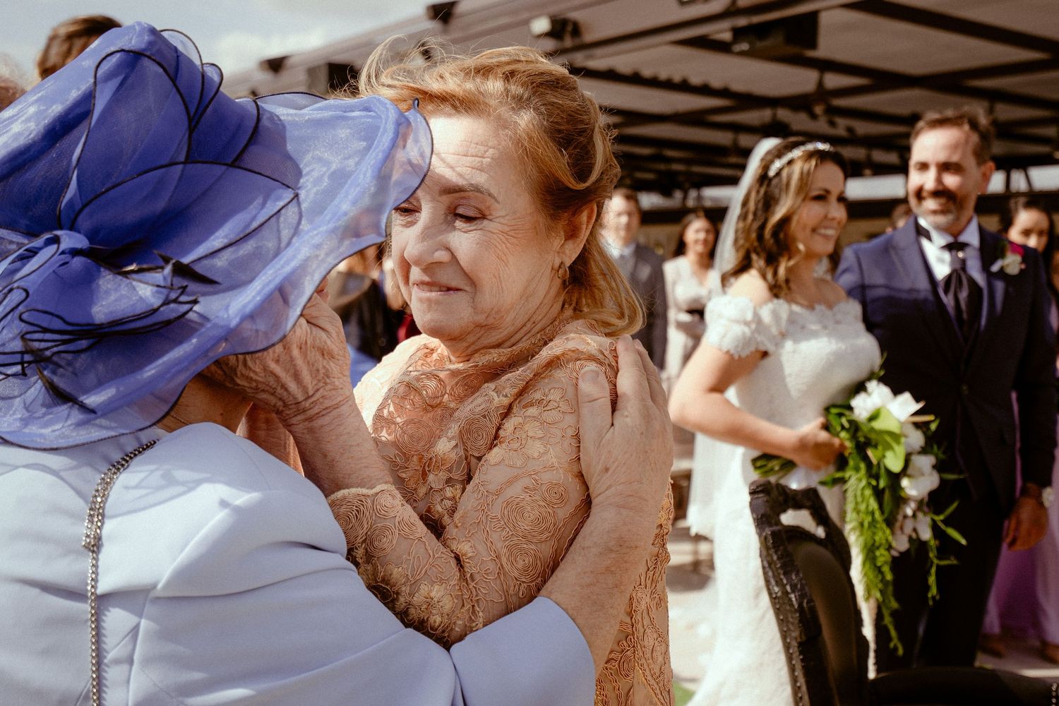 Wedding guests hugging in a warm candid embrace during a reception celebration.
