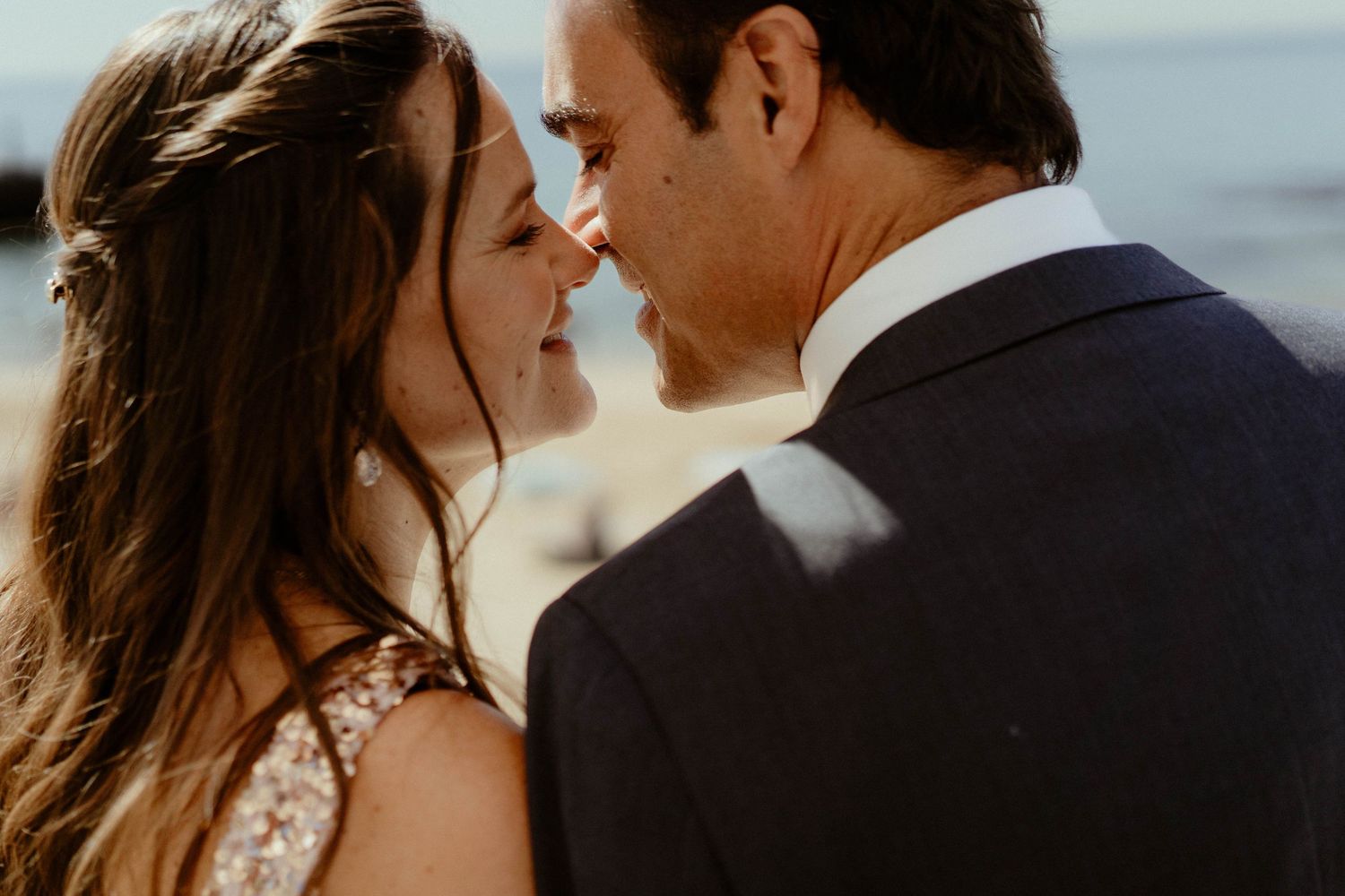 A couple shares an intimate moment at sunset with golden light illuminating their romantic embrace.