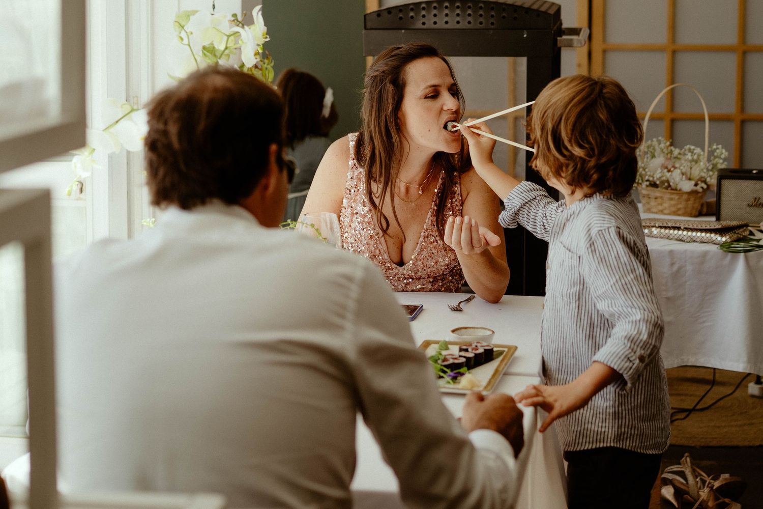 A group of people gathered around a dining table enjoying a meal together in a bright, sunlit room.