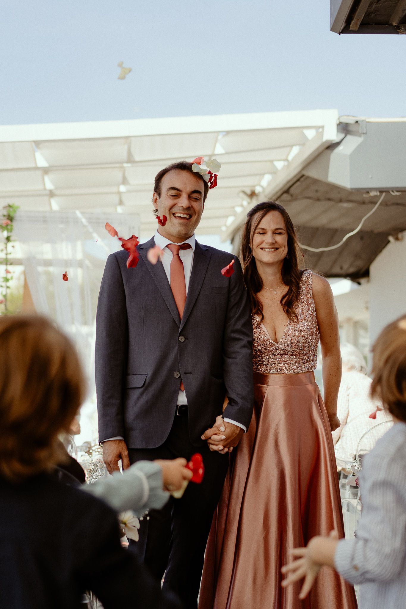 A couple in formal attire dances together at an elegant event under a white tent.