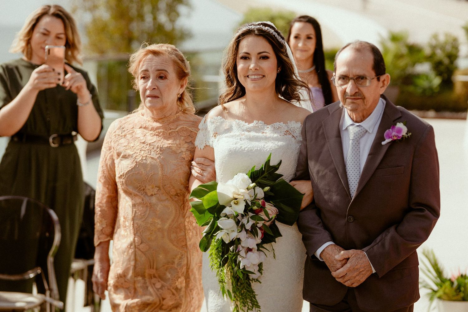 A group of happy wedding guests in peach-colored outfits gather together for a reception photo.