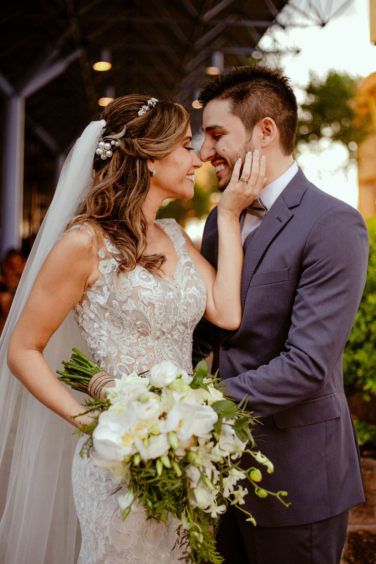 Romantic outdoor wedding series showing newlyweds with elegant white bouquet and lace gown against sunset lighting.