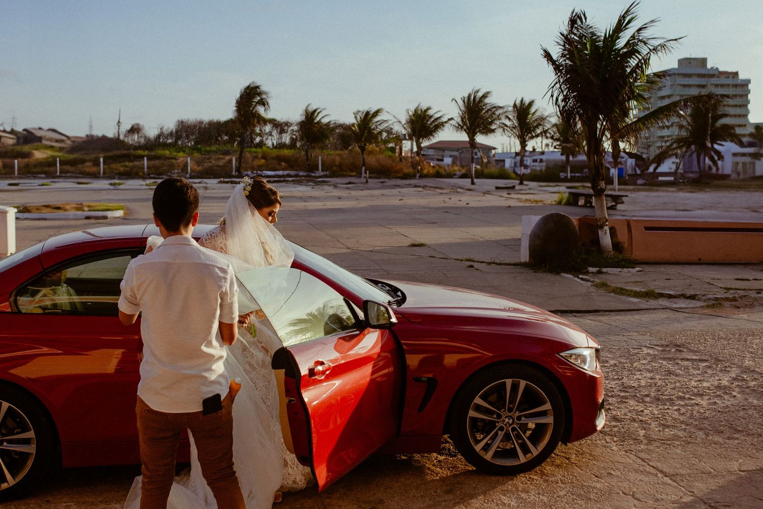 A series of photos showing a bright red Ferrari parked at sunset with windswept palm trees in the background.