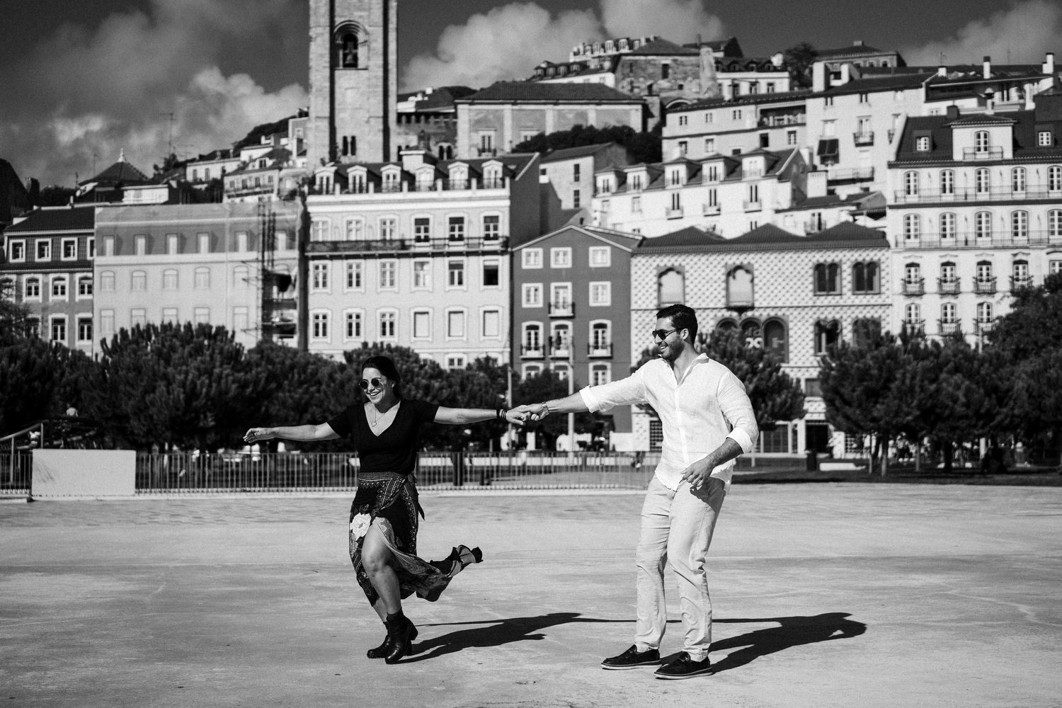 Group of skateboarders performing tricks in a historic European town square with classic architecture in background.