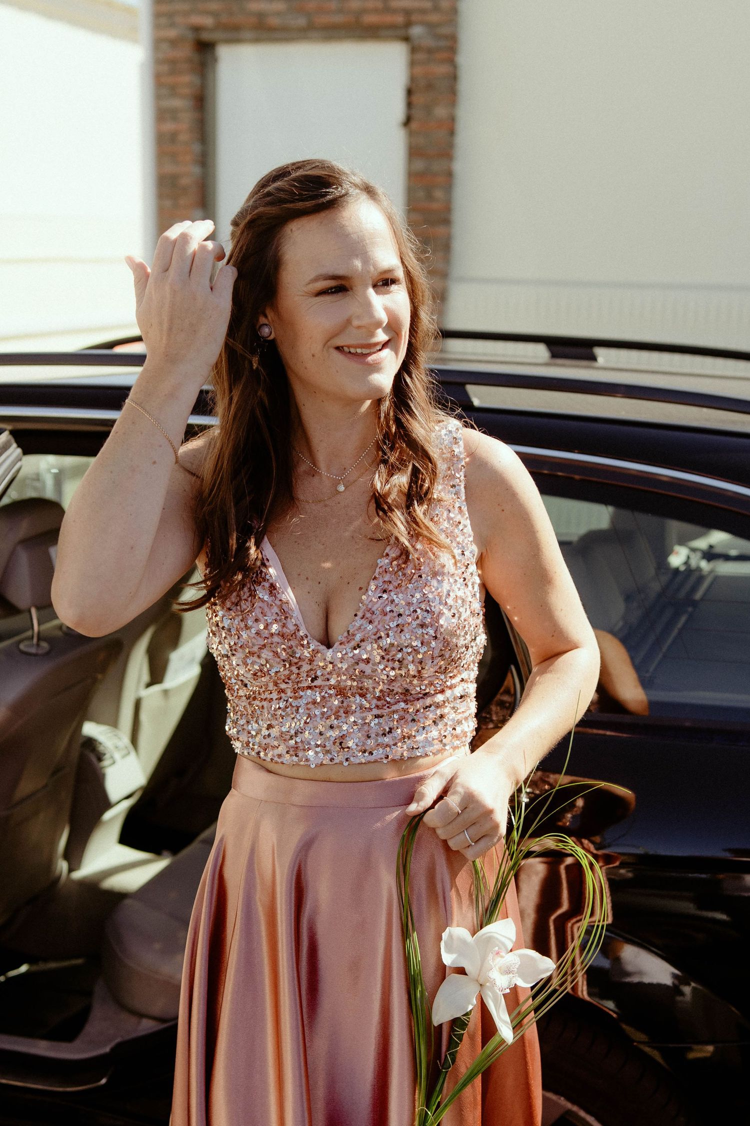 A sequence of photos showing someone in a sparkly pink formal dress posing and twirling outdoors near a car.