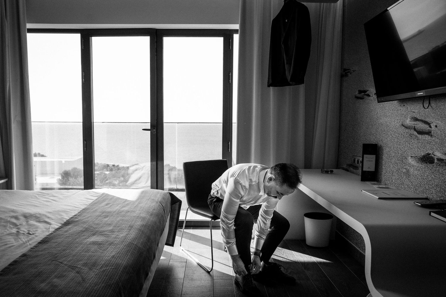 A series of black and white photos showing someone in formal wear getting ready in a room.