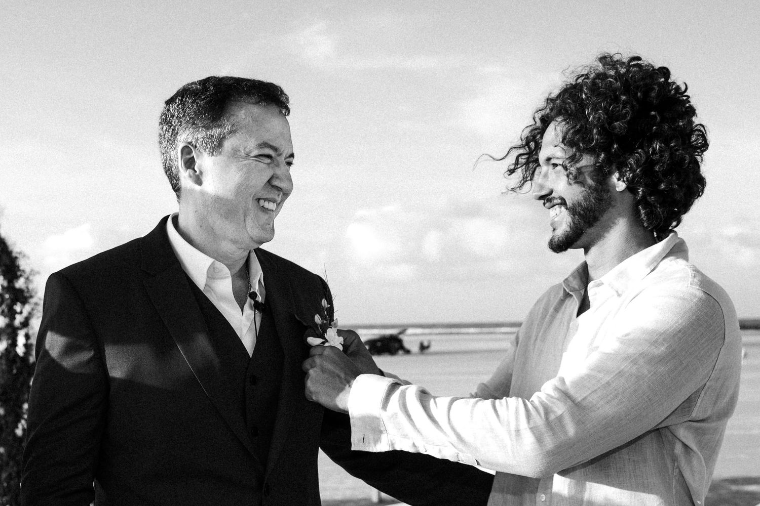Black and white images capturing a joyous celebration with dancing and laughter at an outdoor social gathering.