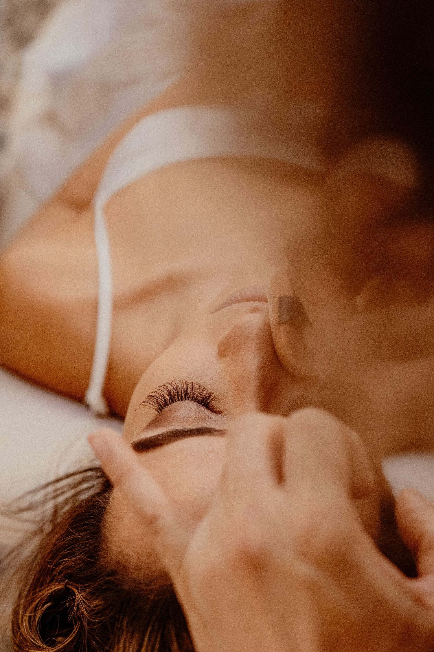 Close-up artistic portrait showing eyelashes and soft skin tones in warm lighting.