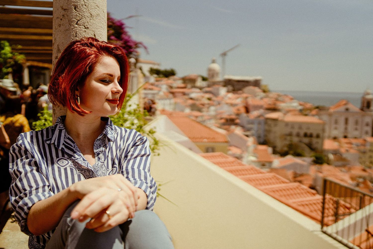 Tourist enjoying scenic rooftop views over Lisbon's historic city center and orange tiled buildings.