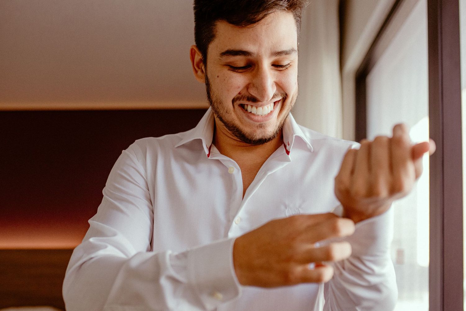 Person in white button-down shirt looking down with a genuine smile.