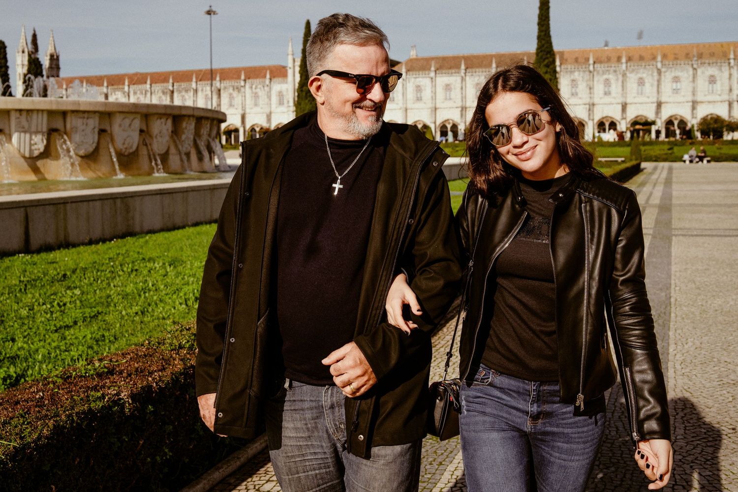 People strolling along historic monastery grounds with white stone architecture in background.