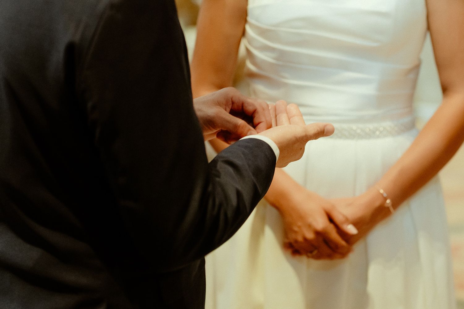 Groom placing a wedding ring on bride's finger during a wedding ceremony.