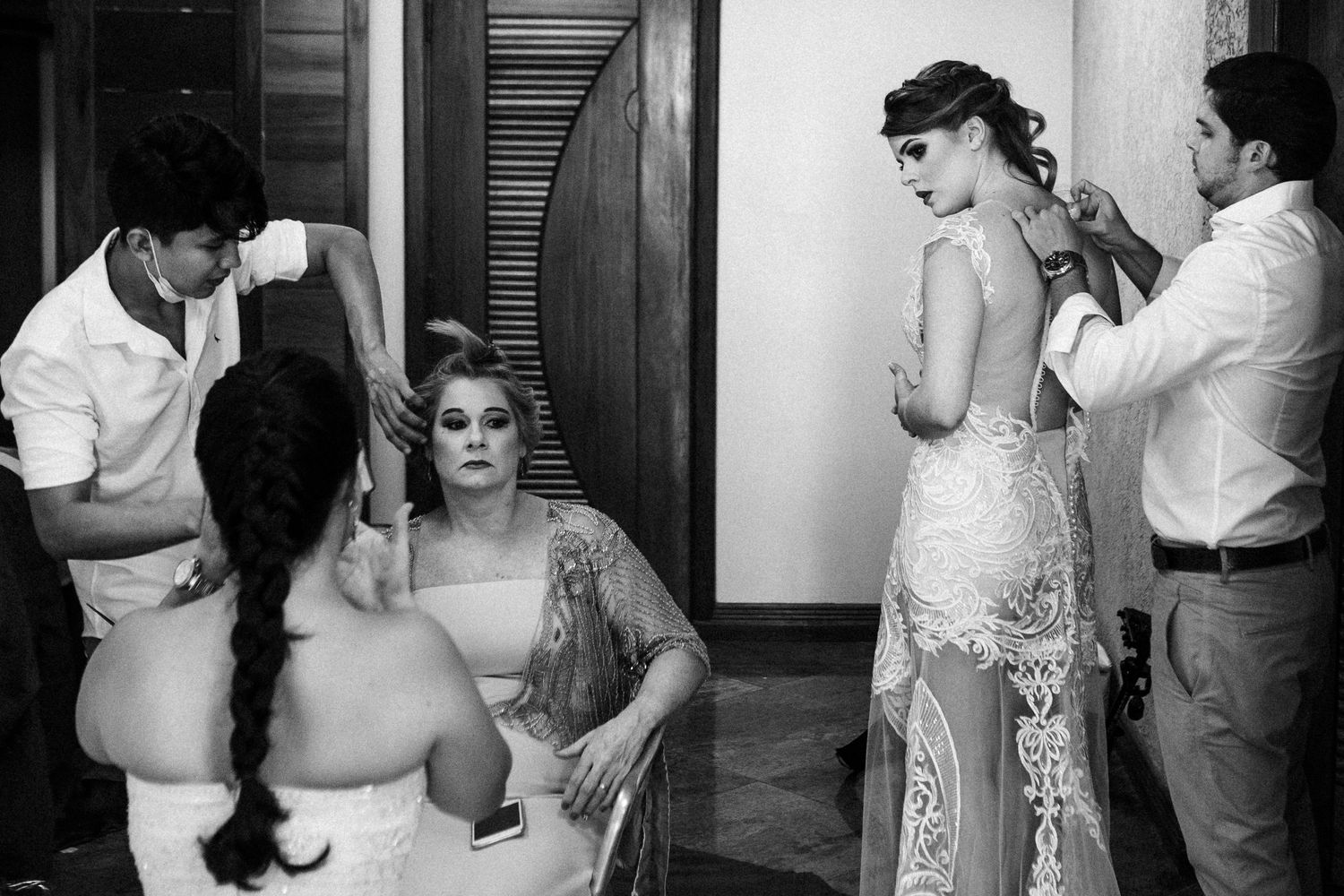 A black and white photograph shows people getting ready backstage at a fashion or performance event.