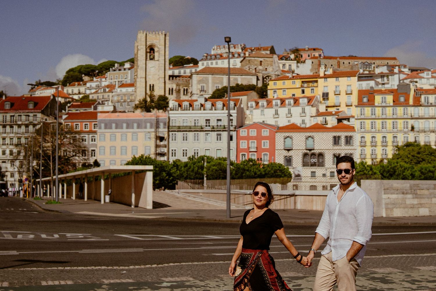 Historic buildings and architecture line a scenic waterfront promenade in Portugal during golden hour.