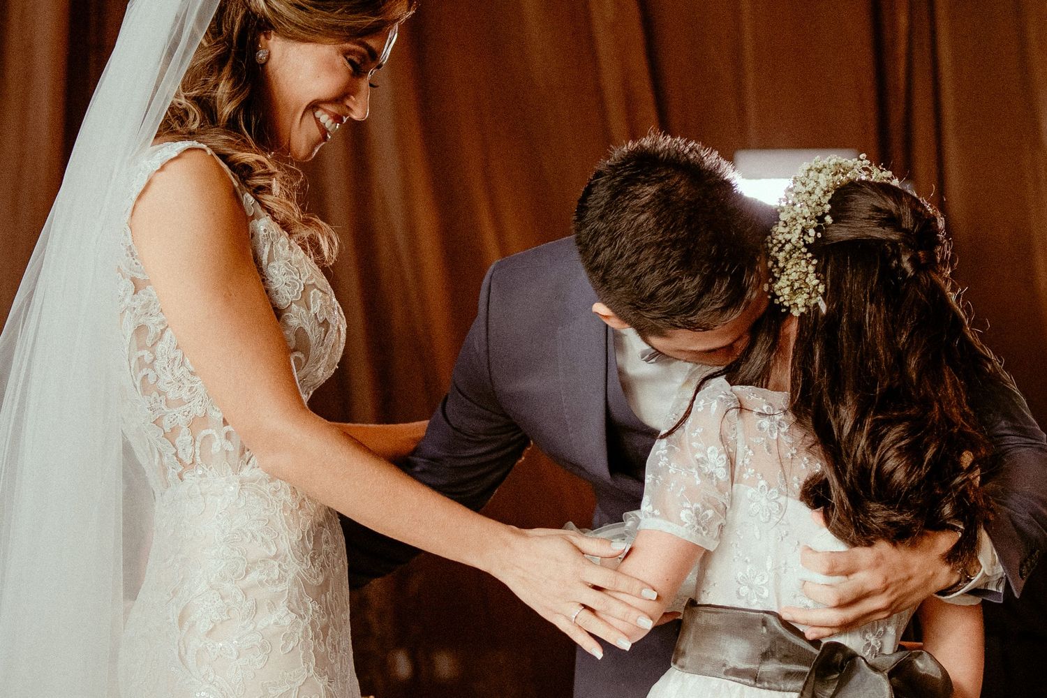Wedding guests share emotional embraces and sweet moments during reception celebration at indoor venue.