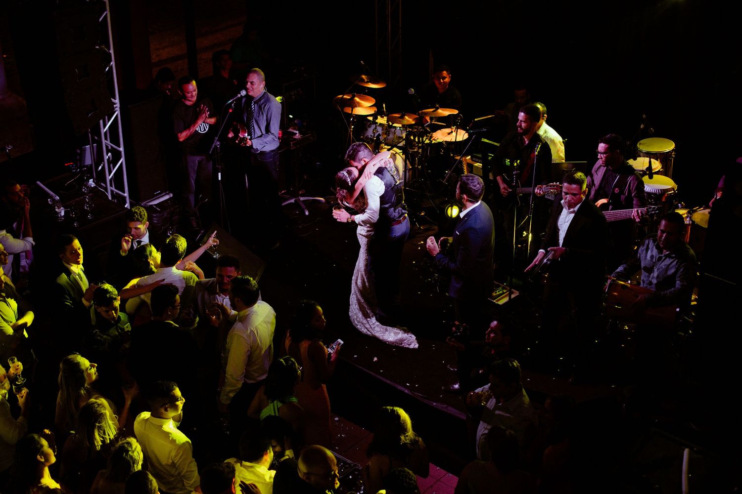 People dancing and enjoying a lively concert or nightclub atmosphere with colorful lighting and dark ambiance.