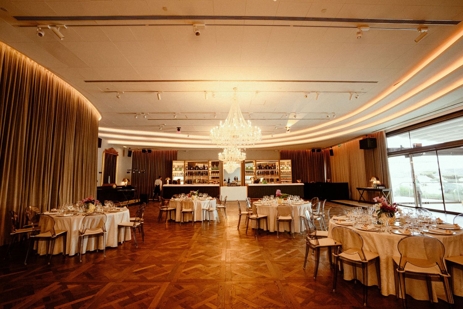 Elegant ballroom with crystal chandelier and round tables set for formal dining.