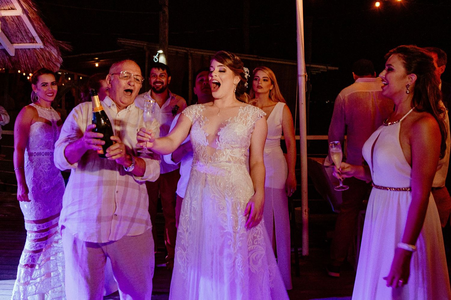 Evening wedding reception with guests dancing under purple mood lighting.