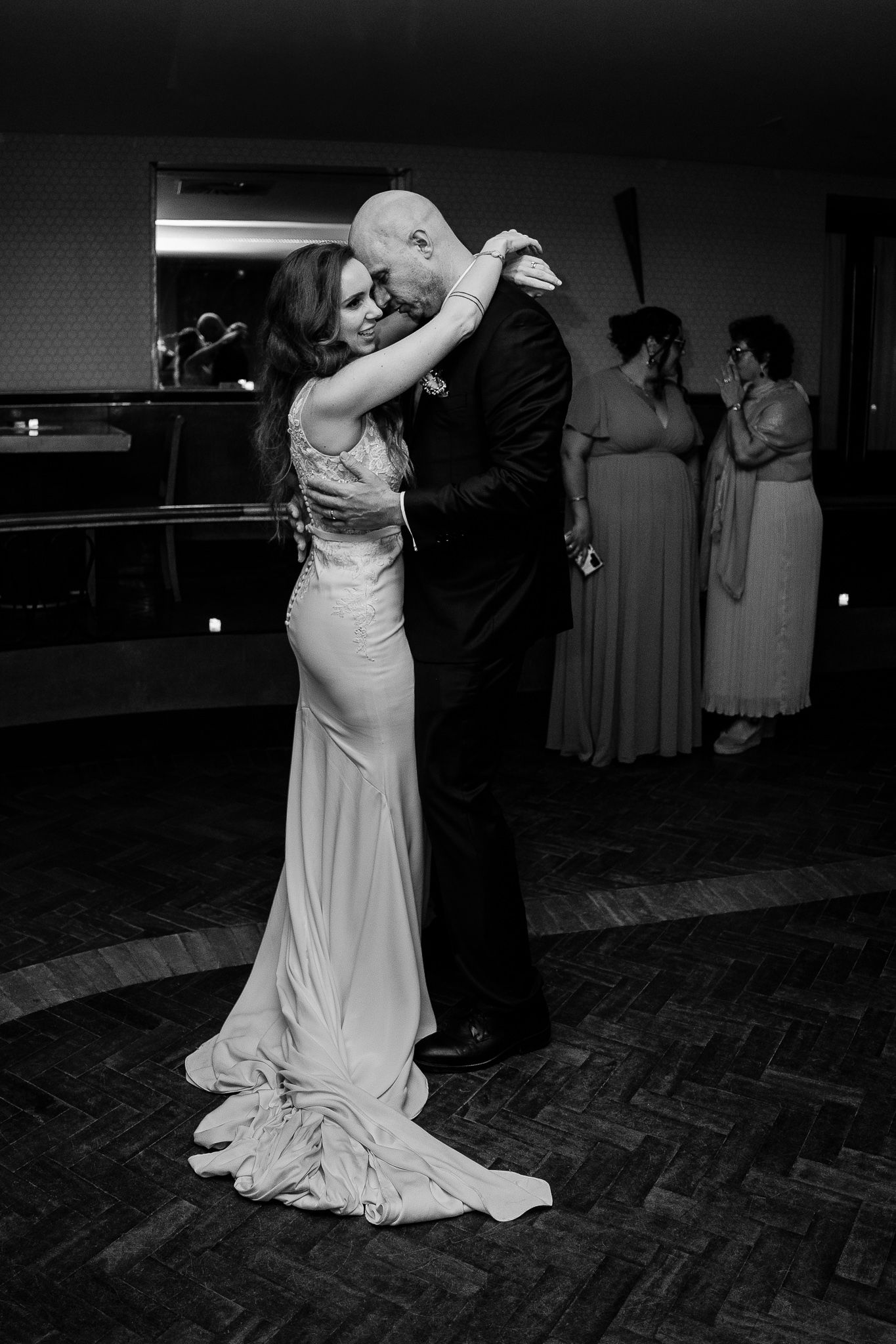 Black and white photo of a couple sharing their first dance at a wedding reception.